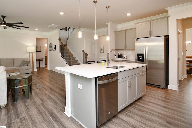 kitchen featuring appliances with stainless steel finishes, light hardwood / wood-style flooring, ceiling fan, and a kitchen island with sink