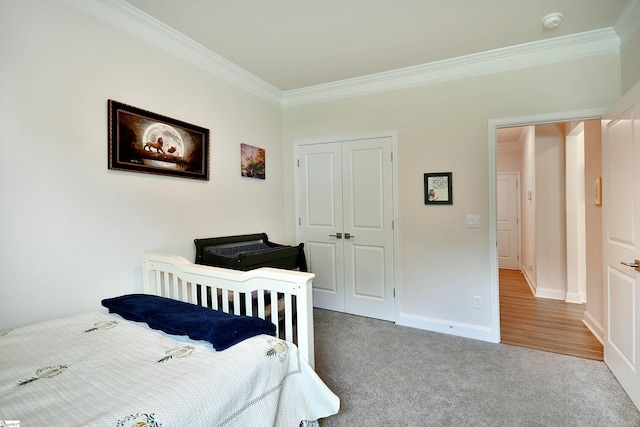carpeted bedroom featuring a closet, baseboards, and ornamental molding