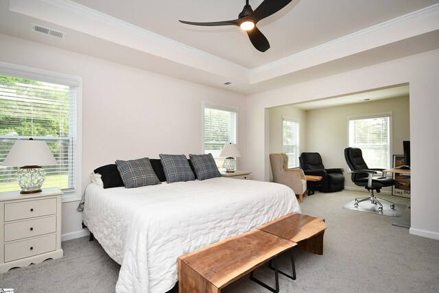 carpeted bedroom featuring multiple windows, ceiling fan, and a tray ceiling