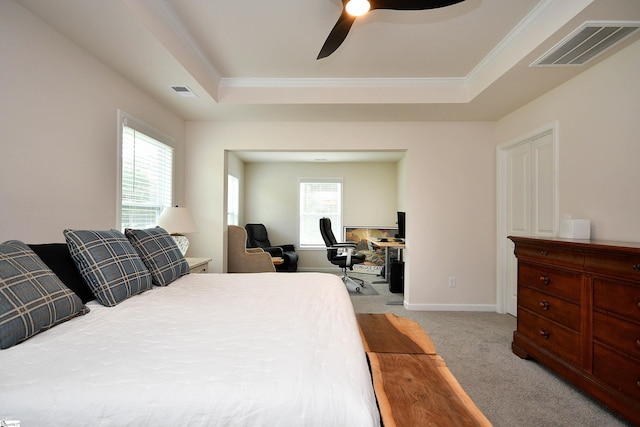 bedroom featuring ceiling fan, multiple windows, light colored carpet, and a tray ceiling