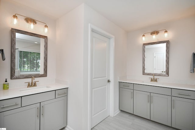 full bath featuring two vanities, baseboards, and a sink
