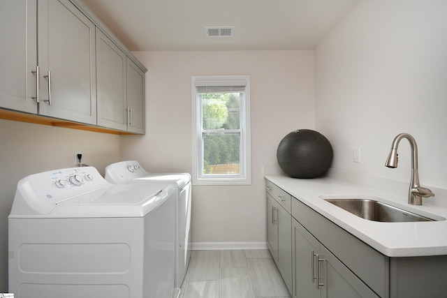 laundry area featuring light tile patterned floors, independent washer and dryer, cabinets, and sink