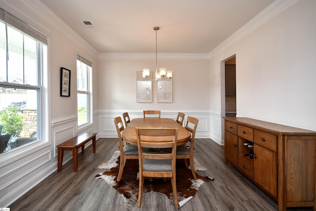 dining space with dark wood finished floors, a wainscoted wall, visible vents, ornamental molding, and a notable chandelier
