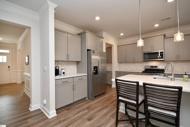 kitchen with decorative backsplash, appliances with stainless steel finishes, hanging light fixtures, and hardwood / wood-style floors