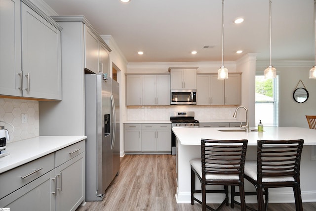 kitchen featuring light wood-type flooring, gray cabinets, appliances with stainless steel finishes, decorative backsplash, and sink