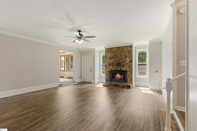 unfurnished living room featuring dark wood-type flooring, a healthy amount of sunlight, a fireplace, and crown molding