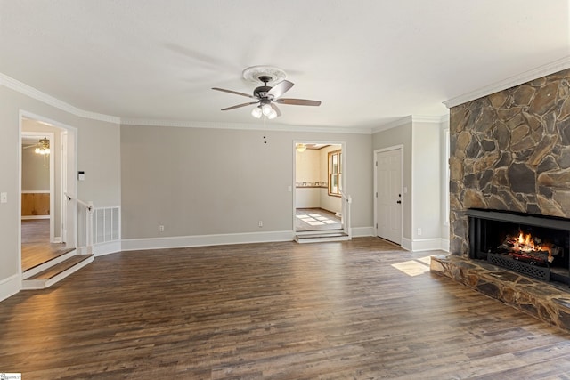 unfurnished living room featuring ceiling fan, ornamental molding, a stone fireplace, and dark hardwood / wood-style flooring