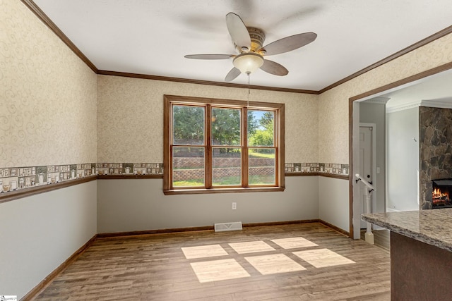 spare room featuring ornamental molding, a fireplace, and light hardwood / wood-style flooring