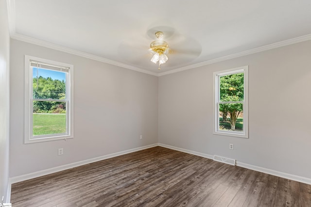 empty room with ornamental molding, a wealth of natural light, and dark hardwood / wood-style flooring