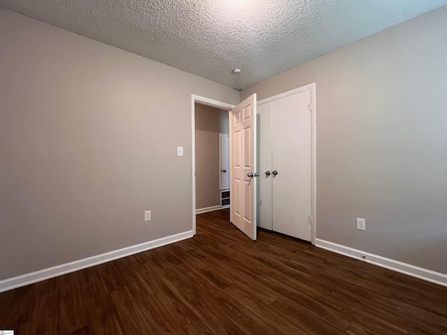 unfurnished bedroom with a textured ceiling and dark wood-type flooring