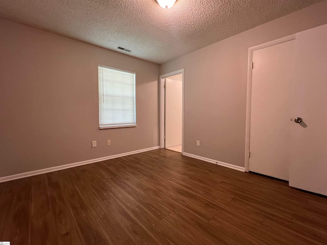 empty room with a textured ceiling and wood-type flooring