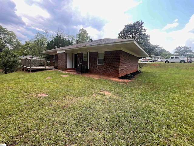 rear view of property featuring a yard and a wooden deck