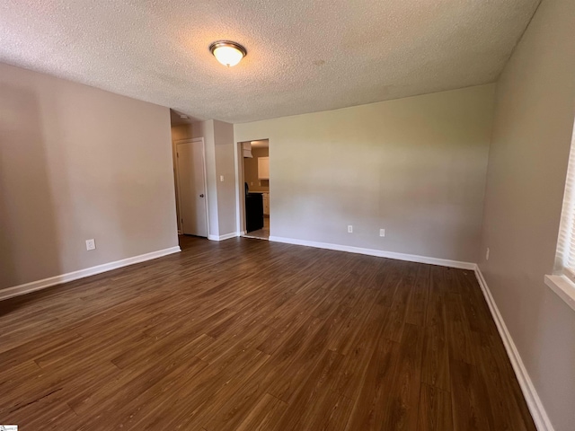 spare room featuring a textured ceiling and dark hardwood / wood-style floors