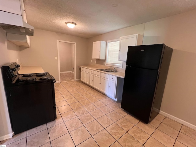 kitchen featuring light tile patterned floors, wall chimney range hood, white cabinets, black refrigerator, and electric stove