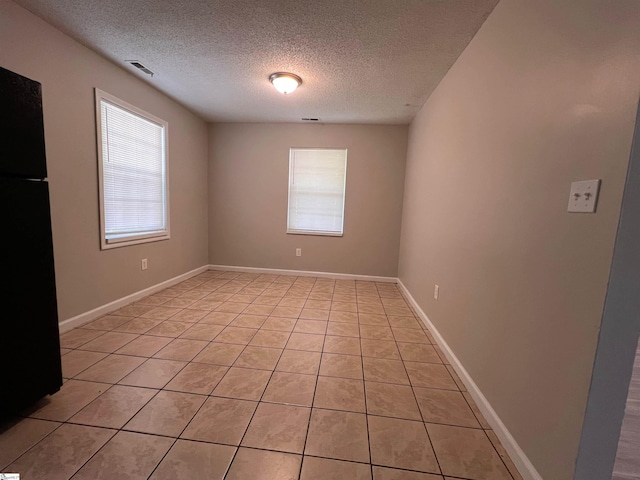 tiled spare room with a textured ceiling