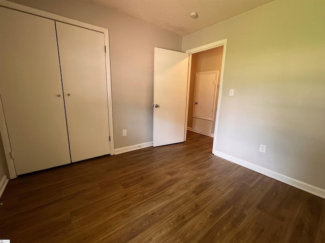 unfurnished bedroom featuring dark hardwood / wood-style flooring, a closet, and a textured ceiling