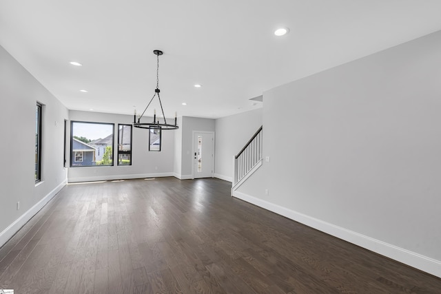 unfurnished dining area featuring a chandelier and dark hardwood / wood-style flooring