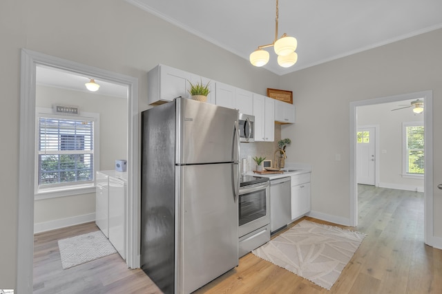 kitchen featuring light wood-style flooring, white cabinets, appliances with stainless steel finishes, washer and clothes dryer, and crown molding