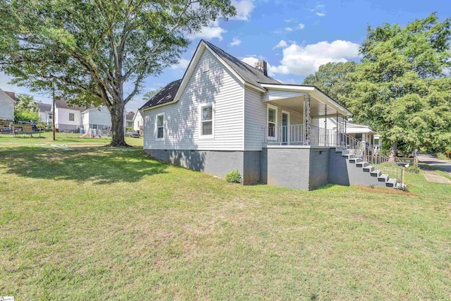 view of property exterior featuring covered porch, stairway, and a lawn
