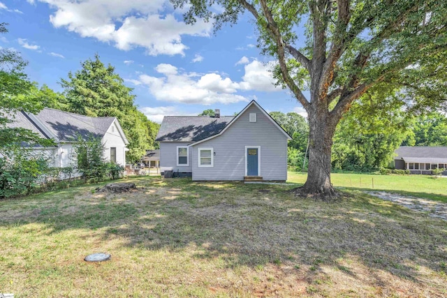 back of property with a yard, a chimney, and fence