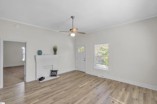 interior space with light wood finished floors, a fireplace, visible vents, and crown molding