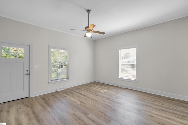 interior space featuring light wood finished floors, visible vents, and crown molding