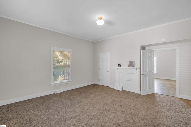 spare room featuring carpet, visible vents, crown molding, and baseboards
