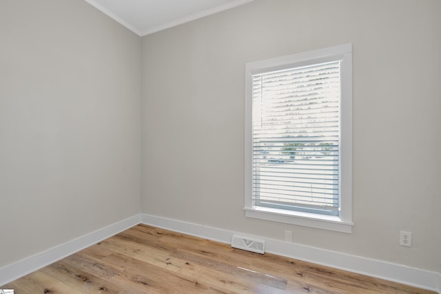 spare room with visible vents, baseboards, a healthy amount of sunlight, light wood-style floors, and ornamental molding