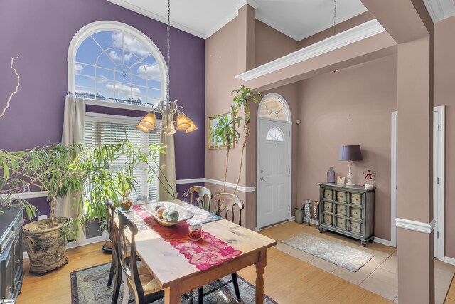 dining space featuring light tile patterned flooring, a towering ceiling, crown molding, and a chandelier