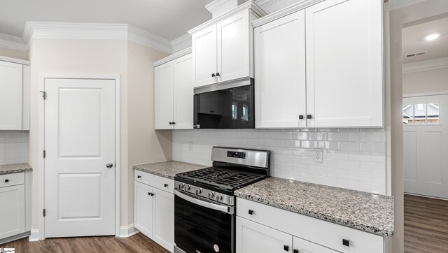 kitchen with appliances with stainless steel finishes, dark wood-type flooring, white cabinetry, and crown molding