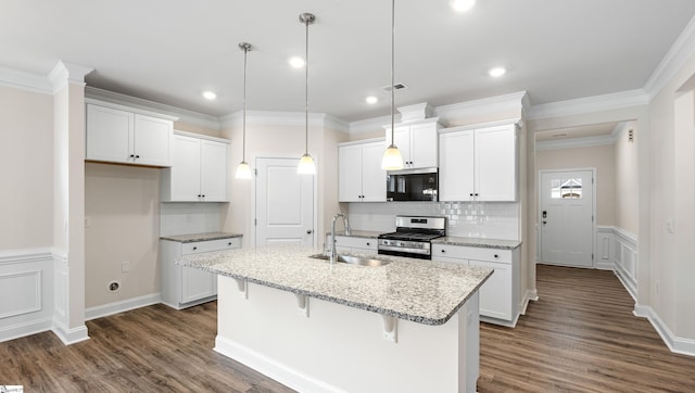 kitchen featuring white cabinets, decorative light fixtures, stainless steel gas range, a kitchen island with sink, and a sink