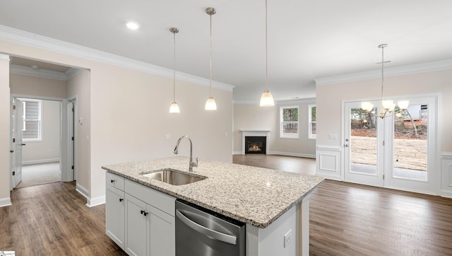 kitchen featuring light stone counters, a sink, white cabinetry, hanging light fixtures, and stainless steel dishwasher