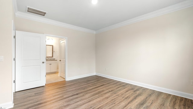 unfurnished room with baseboards, visible vents, wood finished floors, and ornamental molding