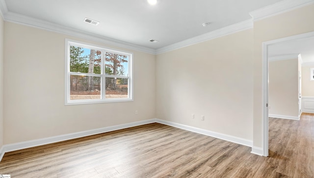 spare room with baseboards, light wood-style flooring, visible vents, and crown molding