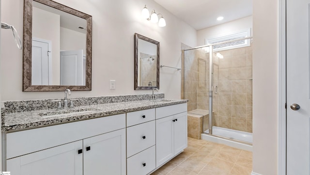 full bathroom with double vanity, a stall shower, tile patterned flooring, and a sink