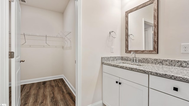 bathroom featuring a spacious closet, baseboards, wood finished floors, and vanity