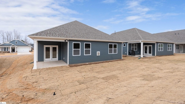 back of property featuring french doors, roof with shingles, and a patio