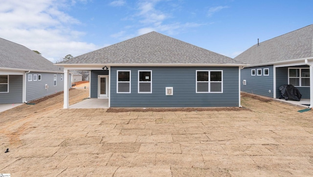 back of property with a patio and a shingled roof