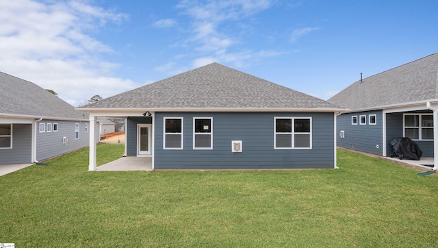 back of property with a patio area, a shingled roof, and a lawn