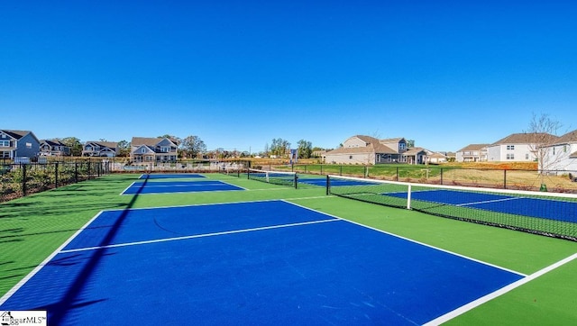 view of tennis court with a residential view, community basketball court, and fence