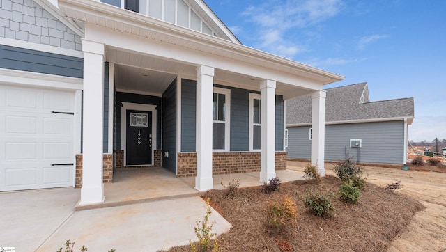 entrance to property featuring an attached garage, brick siding, board and batten siding, and a porch