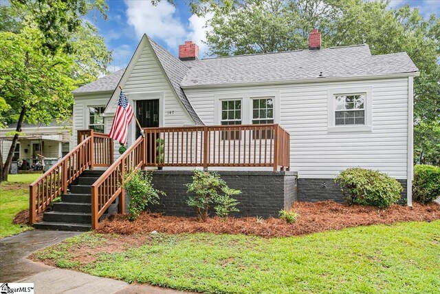 view of front facade with a wooden deck and a front yard