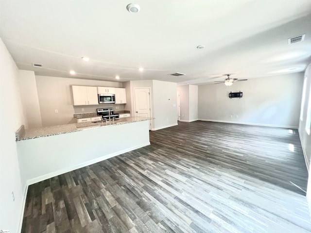 kitchen featuring appliances with stainless steel finishes, white cabinets, light stone counters, ceiling fan, and wood-type flooring