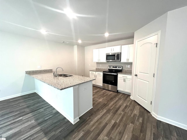 kitchen with appliances with stainless steel finishes, white cabinets, sink, a kitchen breakfast bar, and dark hardwood / wood-style flooring