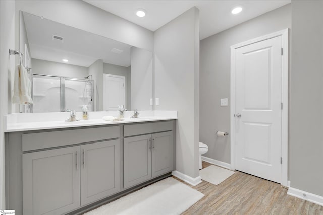 bathroom featuring hardwood / wood-style flooring, vanity, toilet, and a shower with shower door