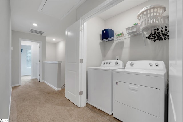 laundry room with independent washer and dryer and light colored carpet