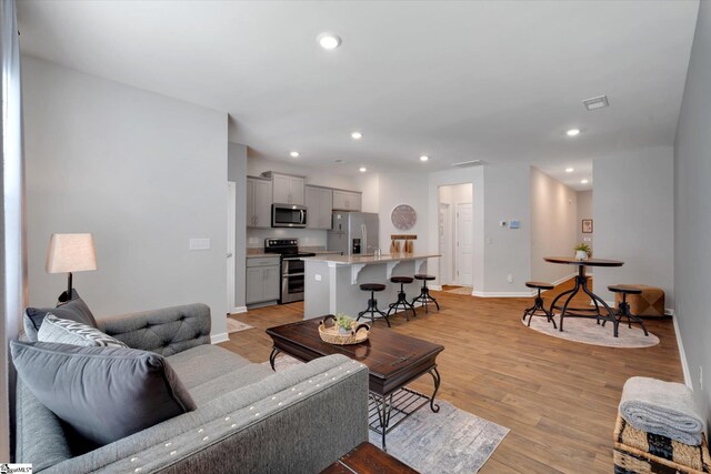 interior space featuring a kitchen bar, appliances with stainless steel finishes, light hardwood / wood-style flooring, and gray cabinets