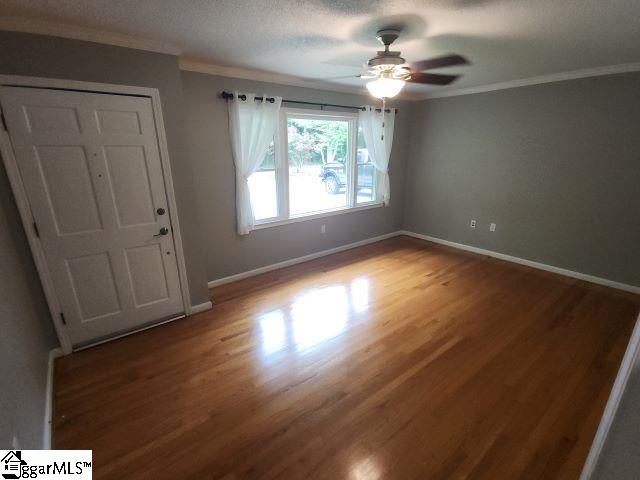 unfurnished room with ceiling fan, wood-type flooring, a textured ceiling, and ornamental molding