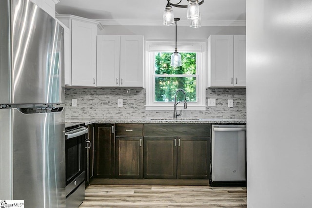 kitchen featuring appliances with stainless steel finishes, tasteful backsplash, white cabinets, light stone counters, and sink