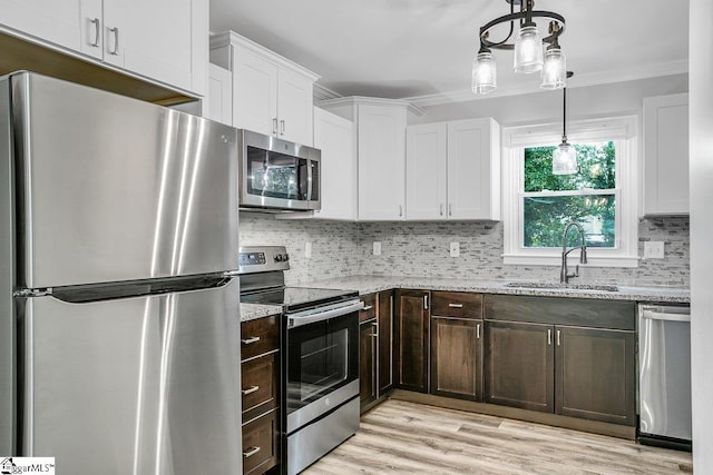 kitchen featuring appliances with stainless steel finishes, white cabinetry, light stone counters, and sink